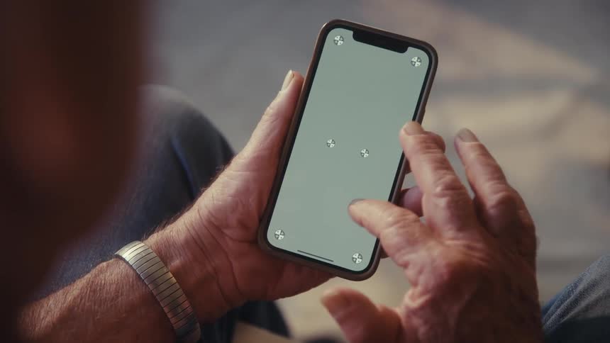 Closeup of elderly person hands holding a smartphone while playing a game
