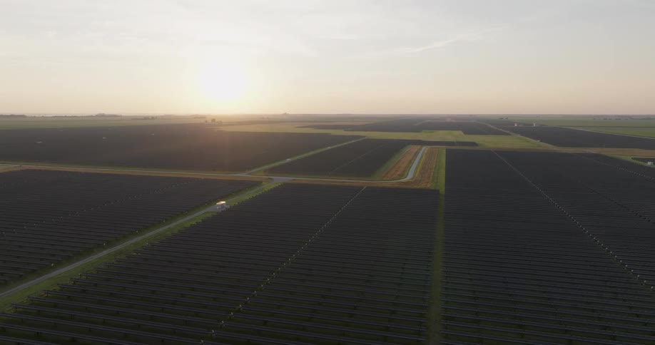The sun is rising over a vast utility scale solar farm installation