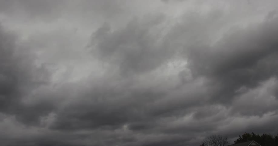 Dark storm clouds hang over distant treetops and rooftops