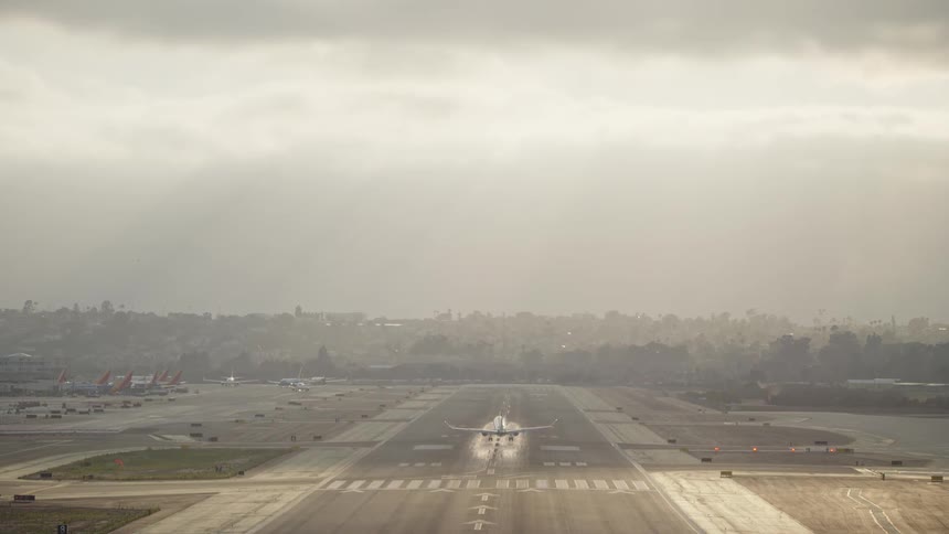The airplane descends closer to the runway in golden hour lighting with its landing gear extended