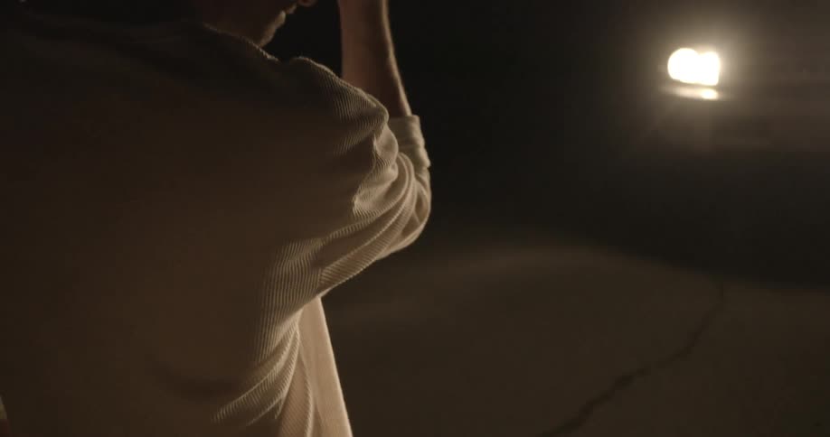 Man walking across a parking lot at night