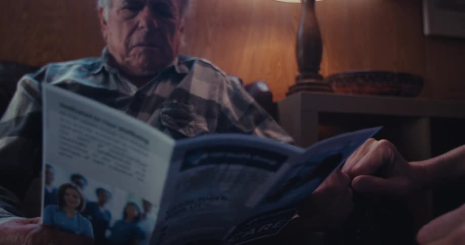 A man is reading a brochure at home