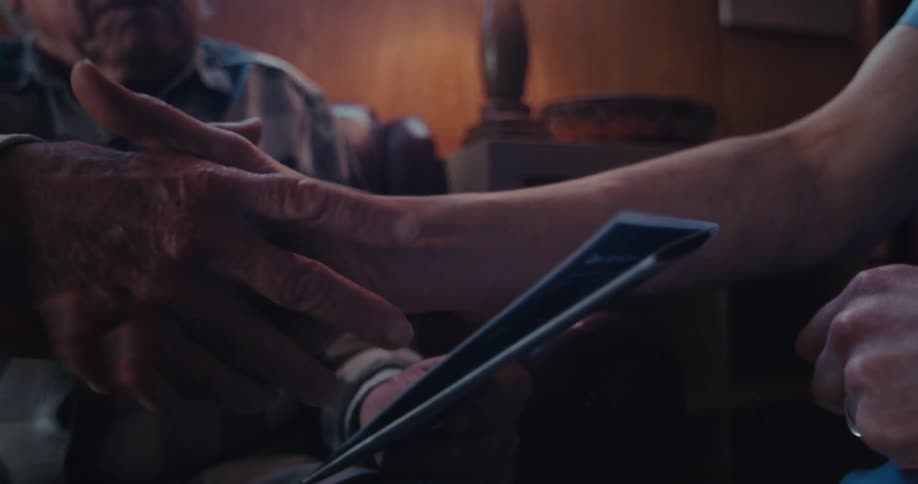Two people exchange a handshake while one holds a folded document