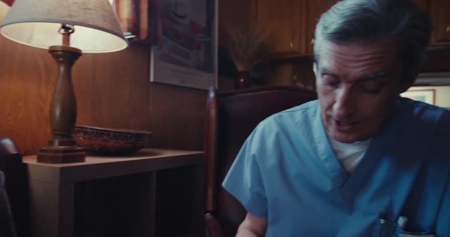 A nurse talking to an elderly man as they both sit indoors during their discussion