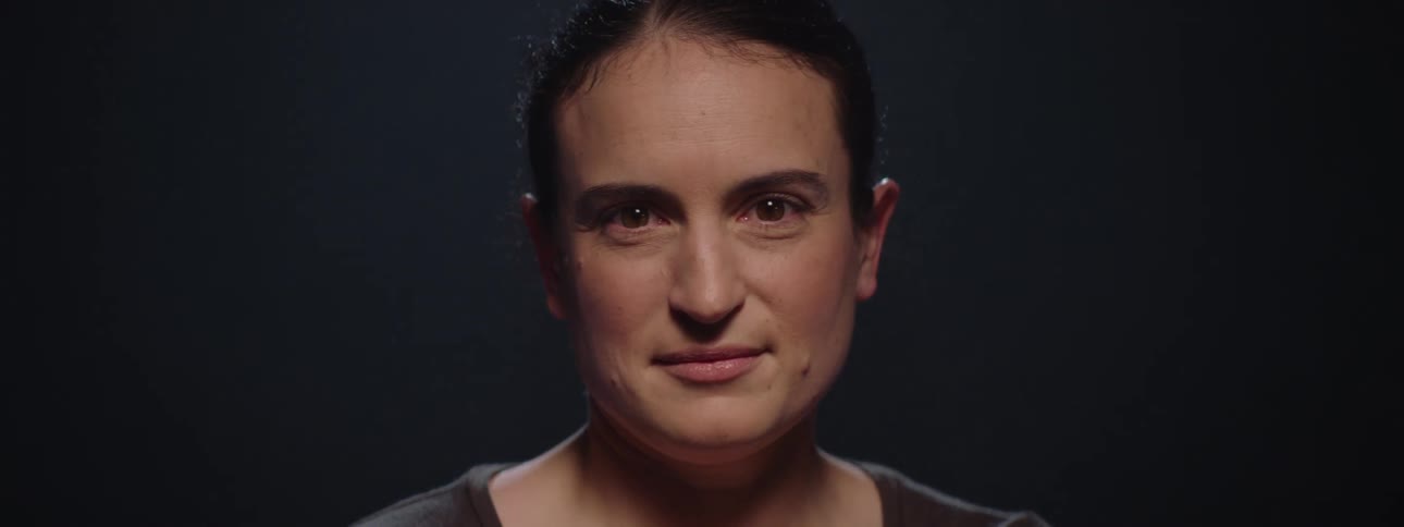 Woman stares into camera under dramatic studio lighting