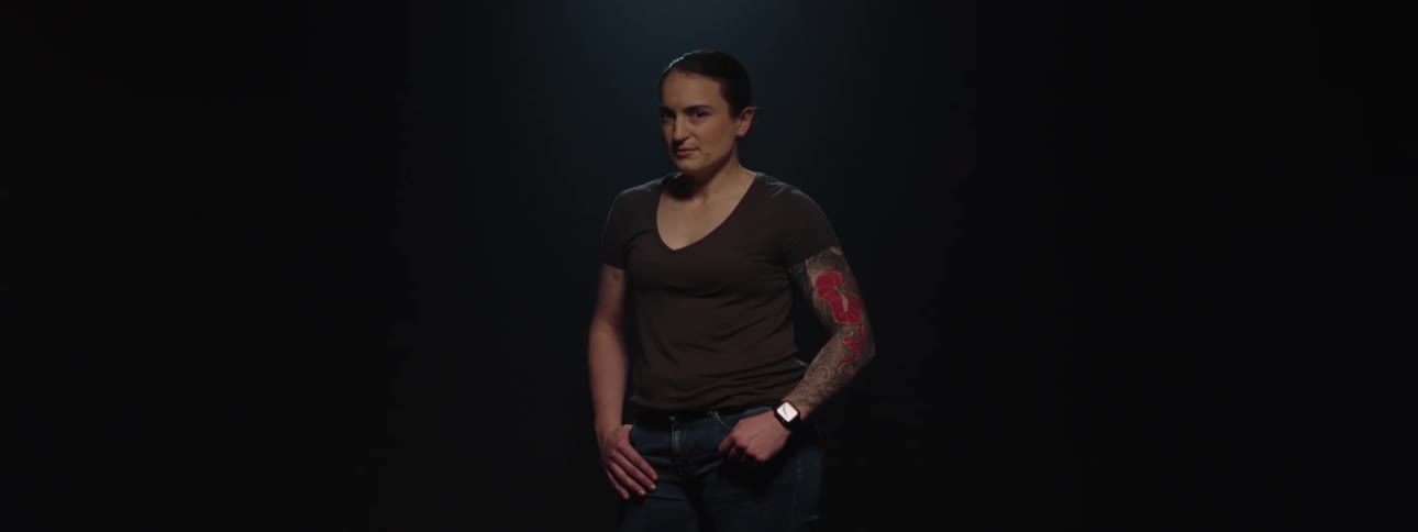 Woman with tied hair and tattooed arm in a lowlight environment