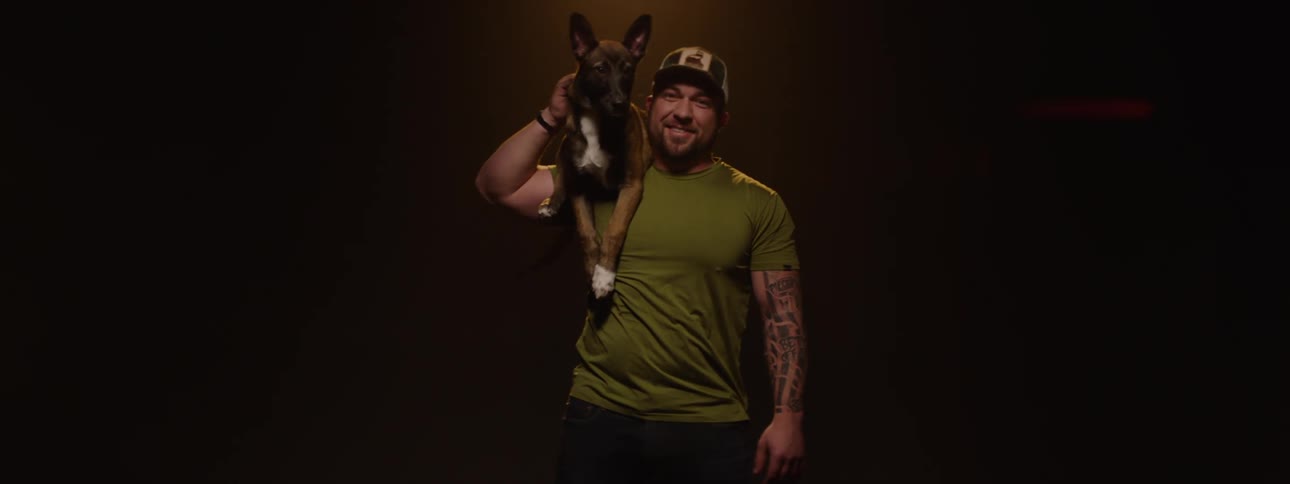 Man in cap holding a dog on his shoulder