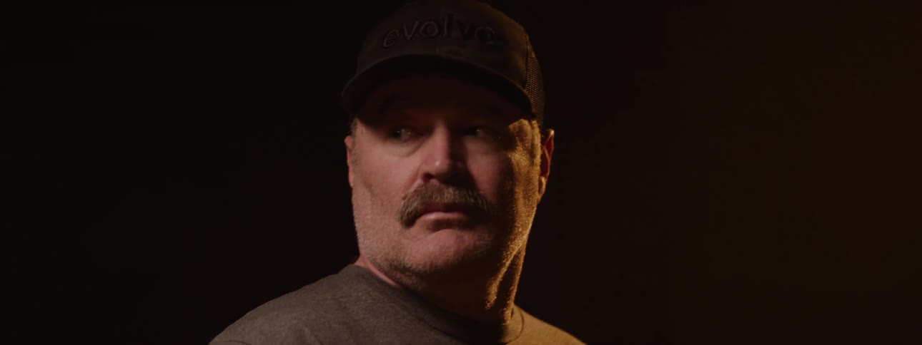 Man with a mustache and cap in a lowlight space