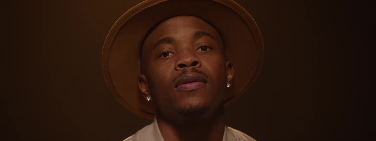 Man wearing a hat in an indoor setting with studio lighting