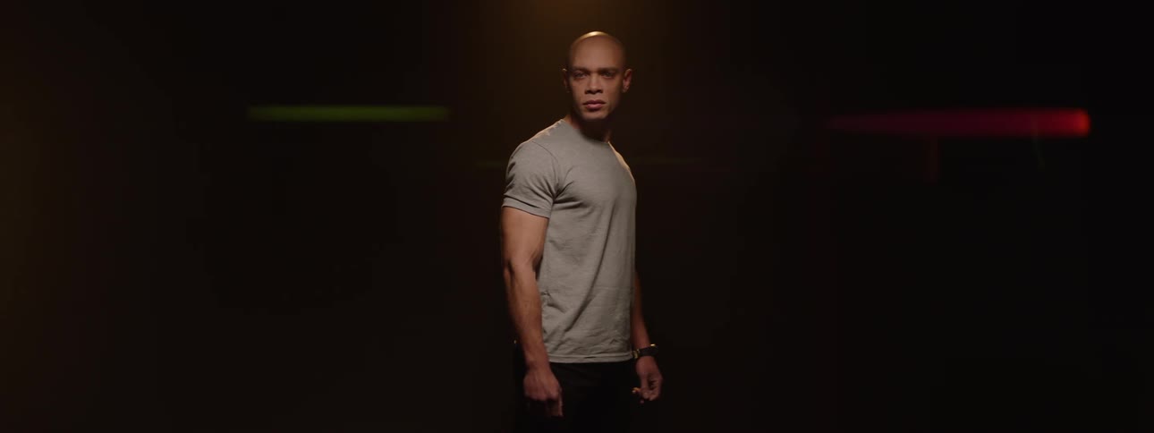 Bald man in a gray tshirt in a lowlight space