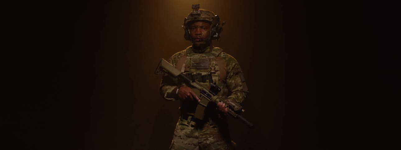 Military man holding a weapon and wearing uniform in an indoor space