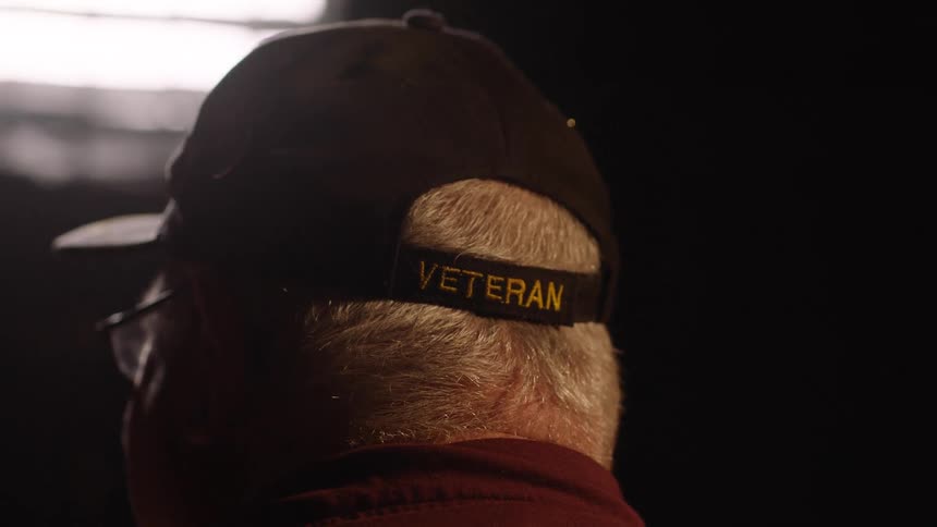 Closeup of an elderly man with a cap that says veteran