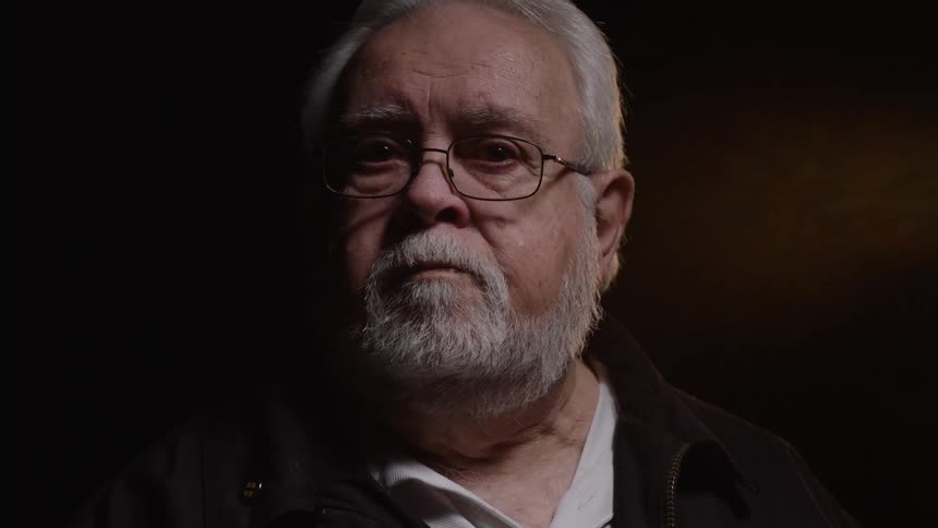 Elderly man with beard and white hair in an indoor space