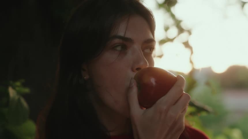 Woman sitting under a tree eating an apple