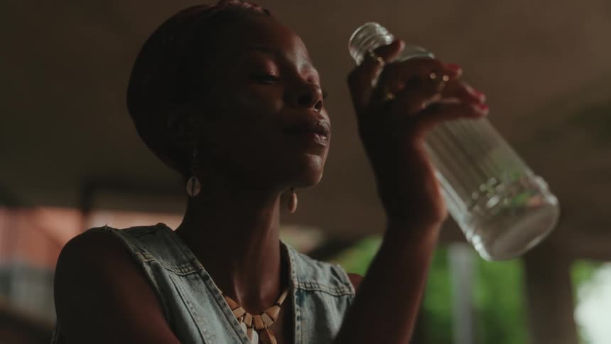 Woman drinking water from a glass bottle