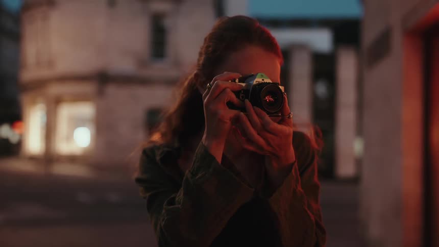 A young woman takes pictures in the city at night