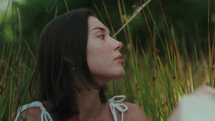 Woman holding a pen while sitting in a field