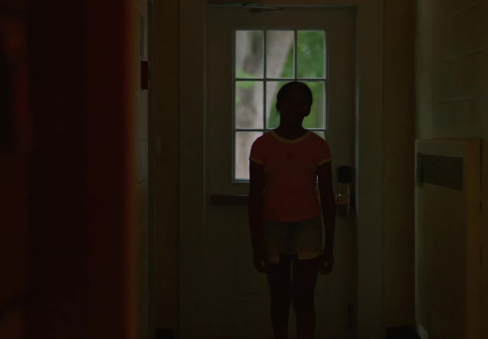 A girl walks inside through an open door