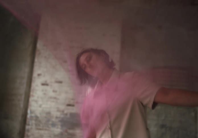 Woman gracefully moves with flowing fabric in a softly lit indoor setting
