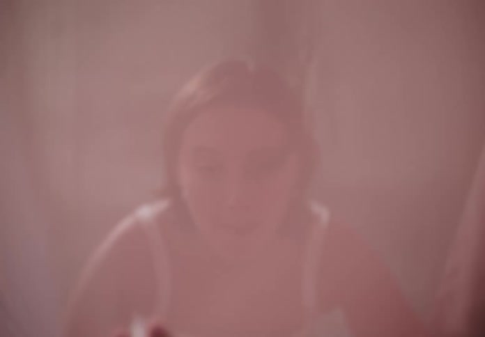 A young woman dancing ballet in a dimly lit room behind a curtain