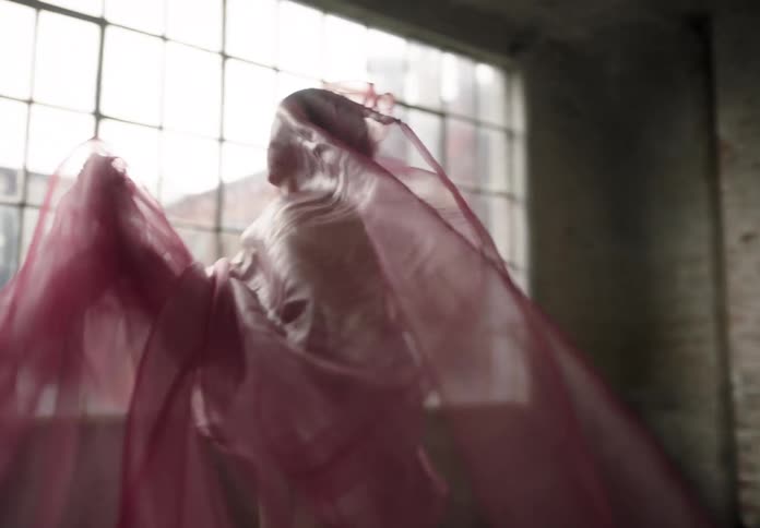 A woman wrapped in a pink sari inside a warehouse building