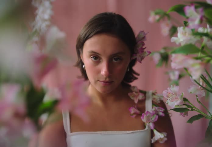 Woman in a dress and short hair with a pink and white flower in her ear