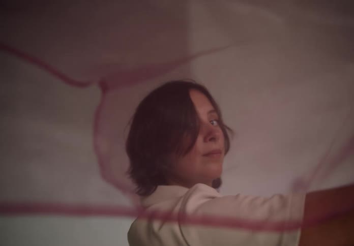Woman holding a pink scarf that flies with the force of the wind