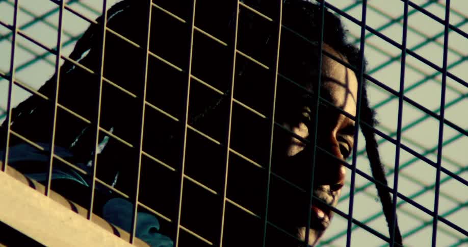 Man bobs back and forth dancing behind a metal grid fence