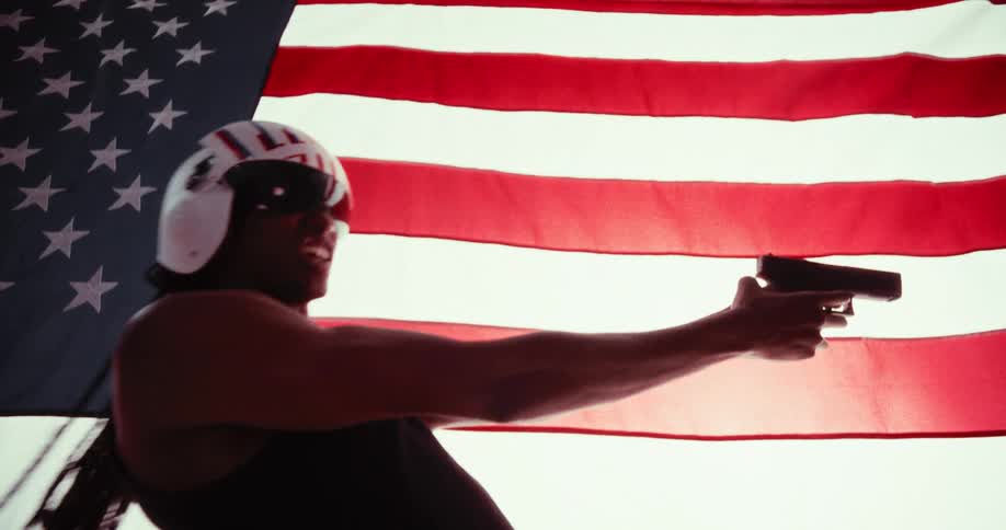 Man in helmet holding pistol next to us flag