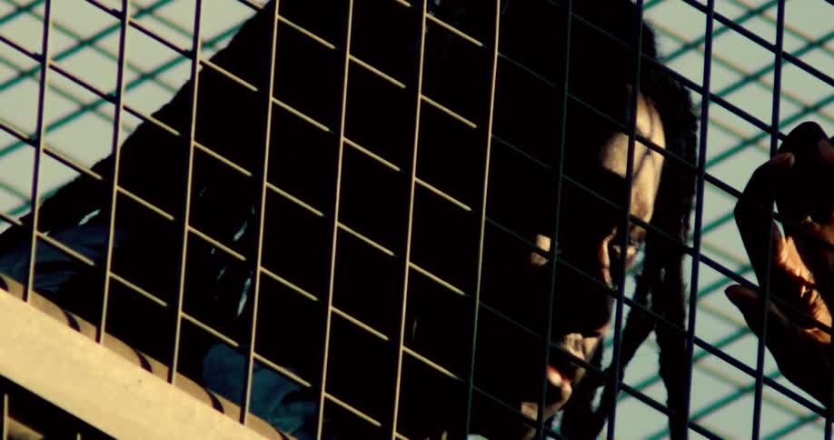 Man shaking his head on a metal fence