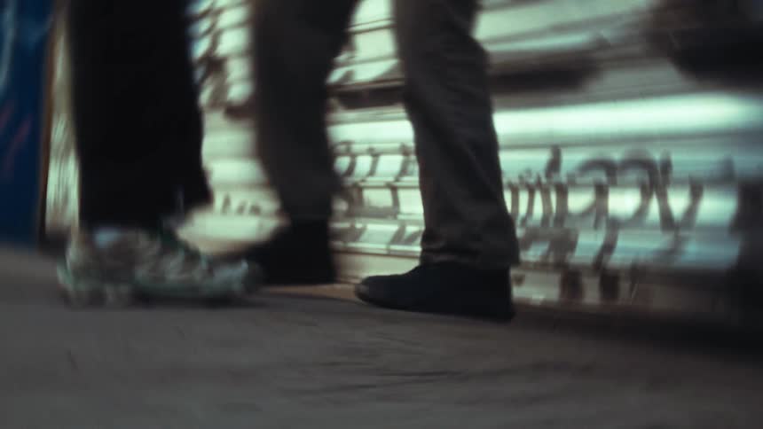 Legs of two people leaning against a metal door with graffiti