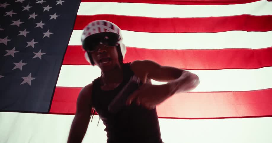 Man in tank top and helmet holding a pistol