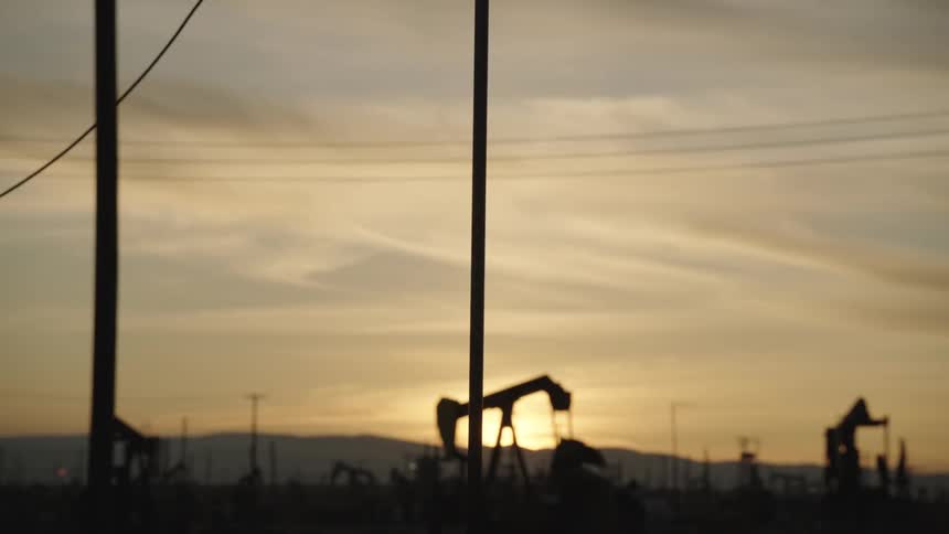 Striking silhouette of an oil well pumpjack against the sunset