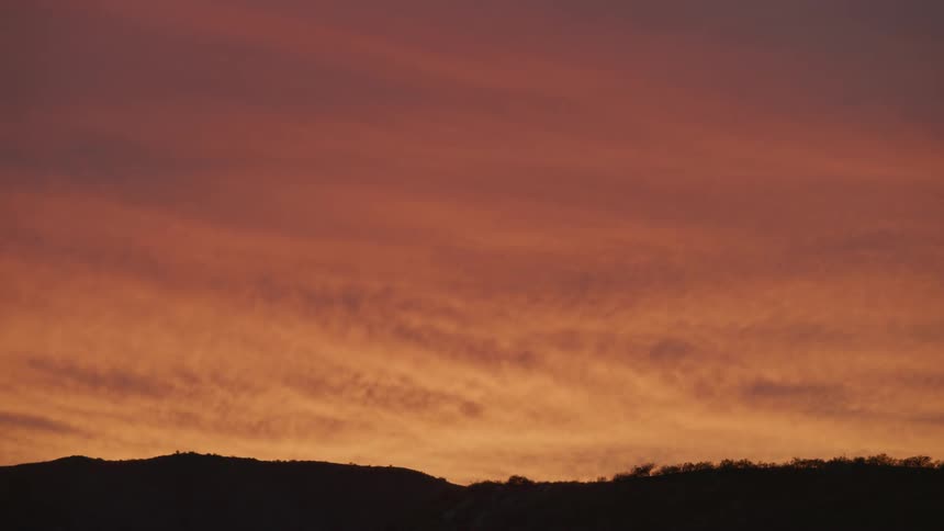 Silhouette of mountains against a reddish dawn sky