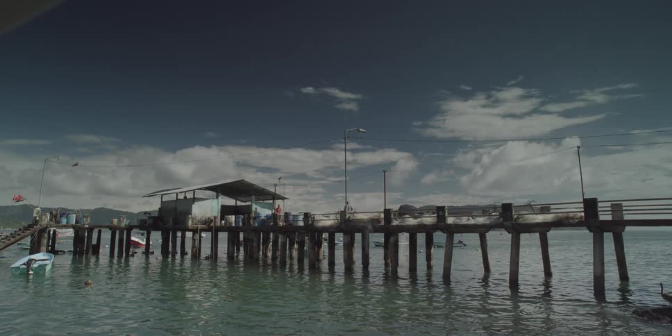 Rustic wooden pier extending into calm greenishblue water