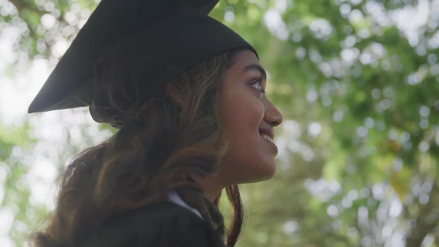 Young woman wearing a graduation cap in a treelined setting