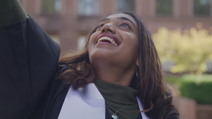 Woman throwing graduation cap up with happy expression