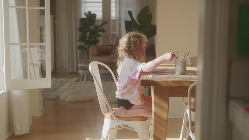 A girl is painting on the dining room table