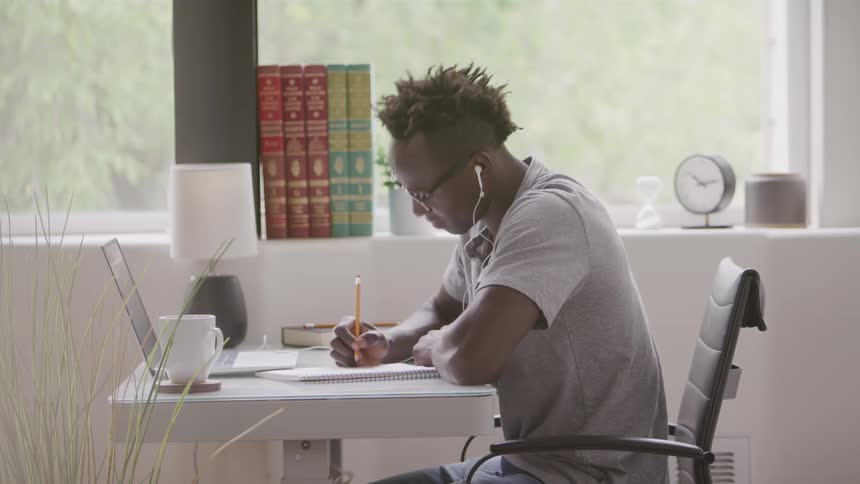 The man writes and looks at his laptop
