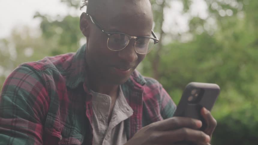 Man wearing glasses texts while outdoors during the daytime