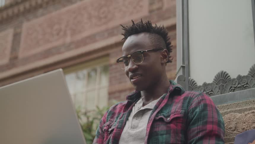 The man smiles while using his laptop