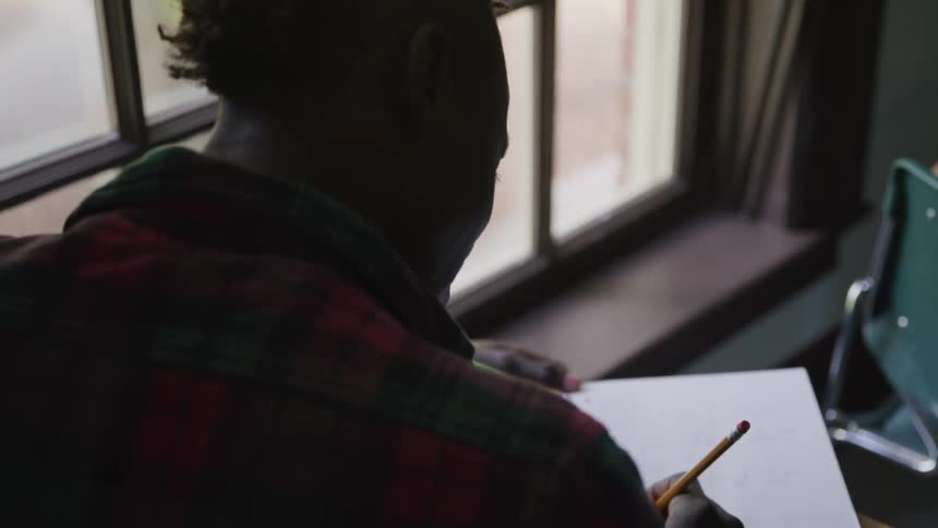 A student is using a pencil to write in his notebook