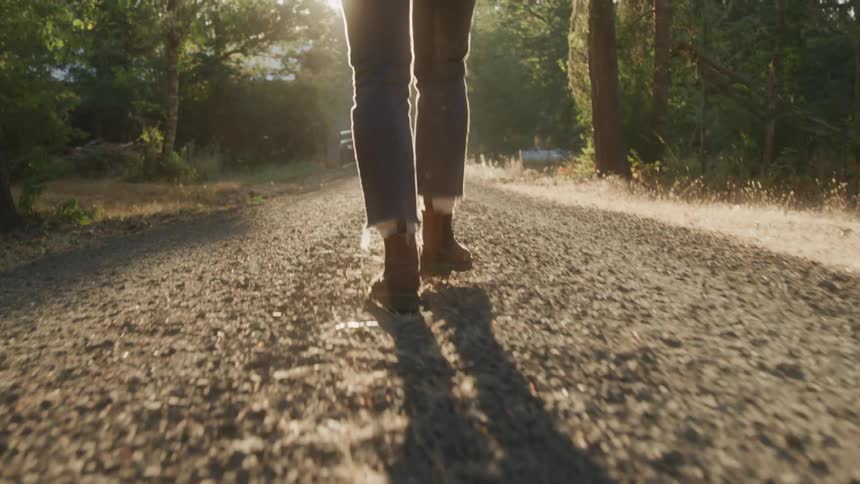Feet of a person walking outdoors with trees around
