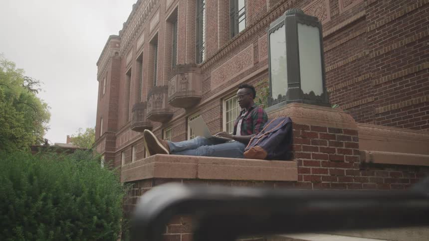 Man sitting on a wall writing in a notebook