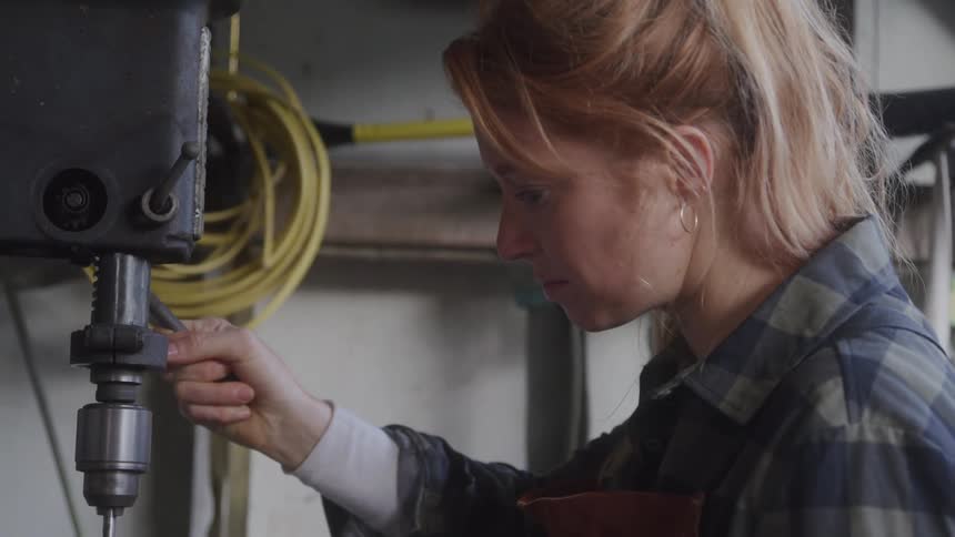 The woman is using a drill machine
