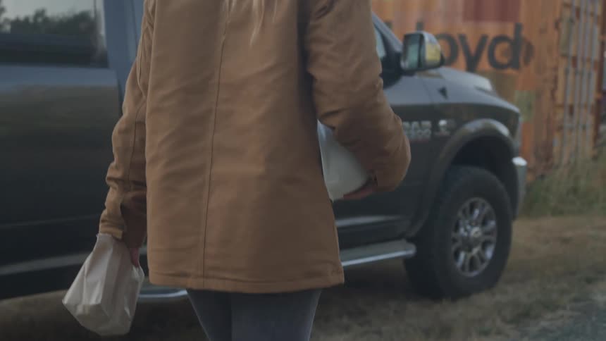 The woman is walking past the truck