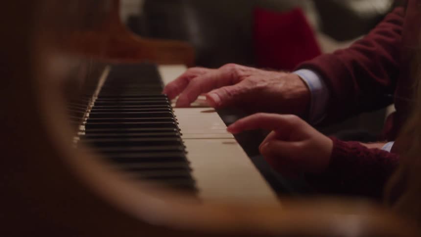 The video shows an extreme closeup of a persons hands playing the piano with natural light illuminating the keys and their movements