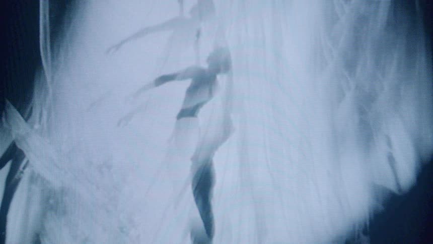 Silhouetted figure performs graceful dance movements behind a translucent curtain
