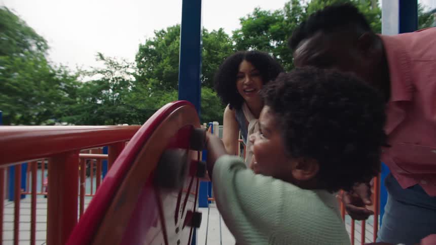 Family laughs and plays together at a playground