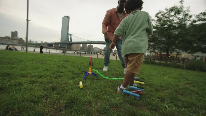 Father and son riding a toy outdoors in a grassy park